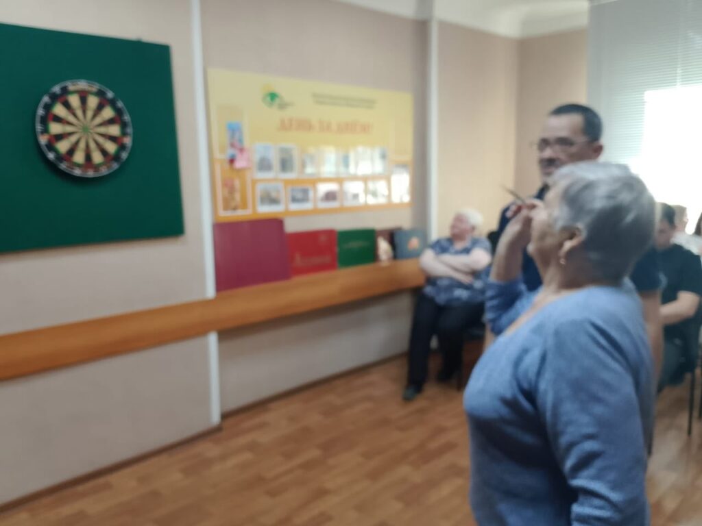 участница соревнований целится дротиком в мишень