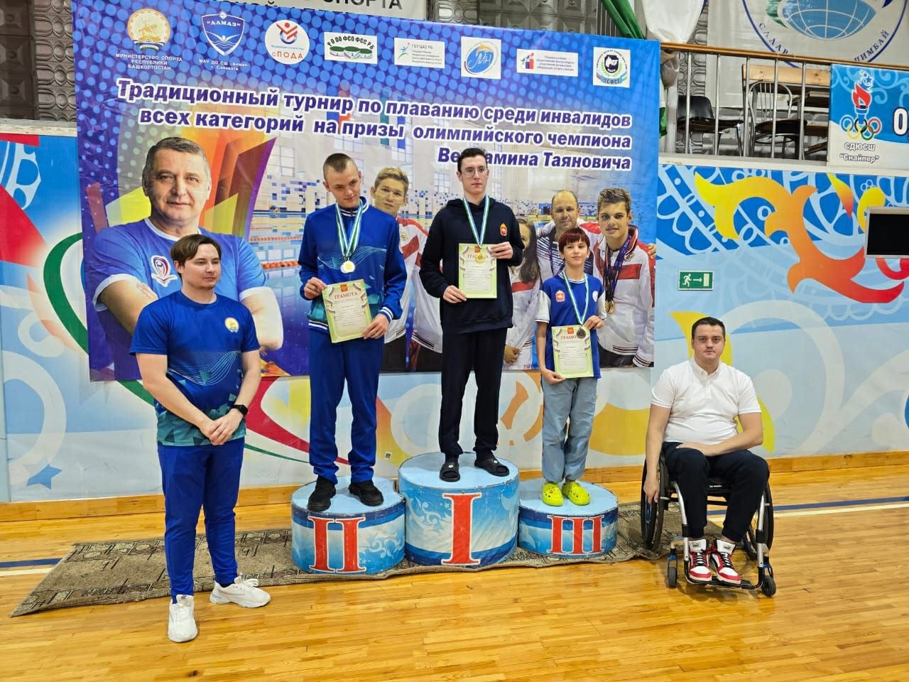 спортсмены победители стоят на пьедестале с наградами