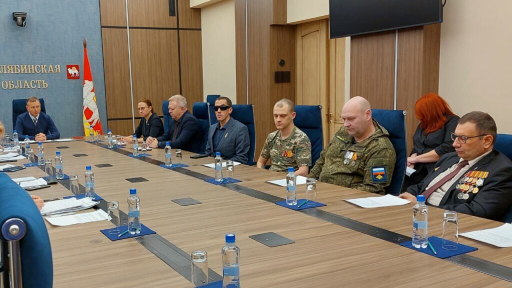 александр рожков за столом раядом с участниками сво и представителем фонда защитники отечества