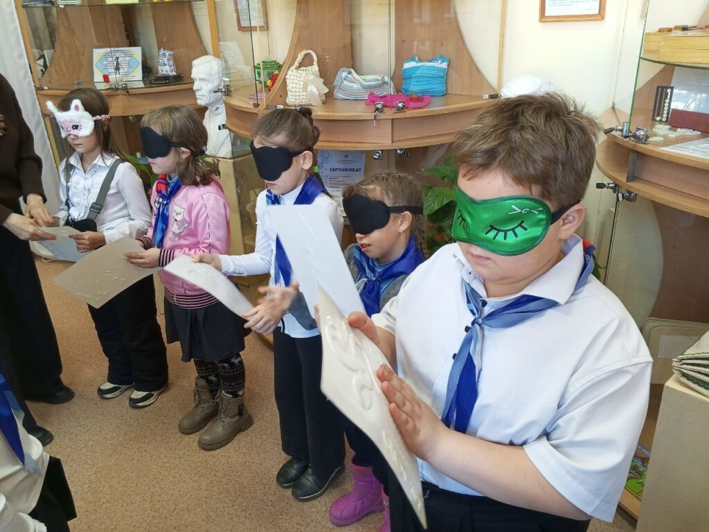 дети в закрывающих глаза масках тактильно определяют что изображено на рельефном рисунке