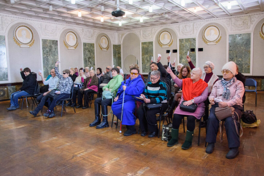 делегаты конференции голосуют, подняв вверх мандаты