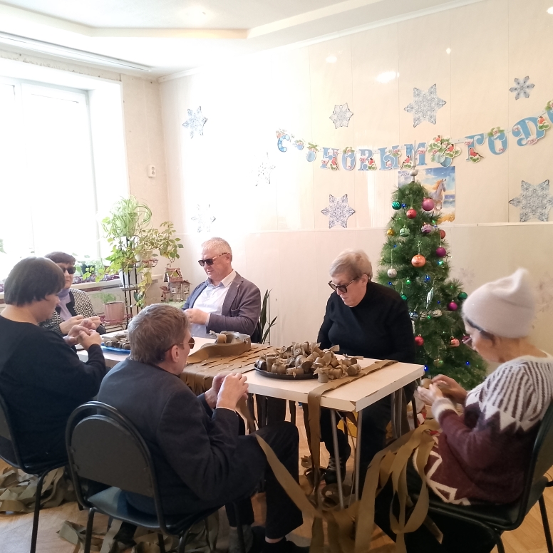 группа активистов сидит за общим столом и плетет сети