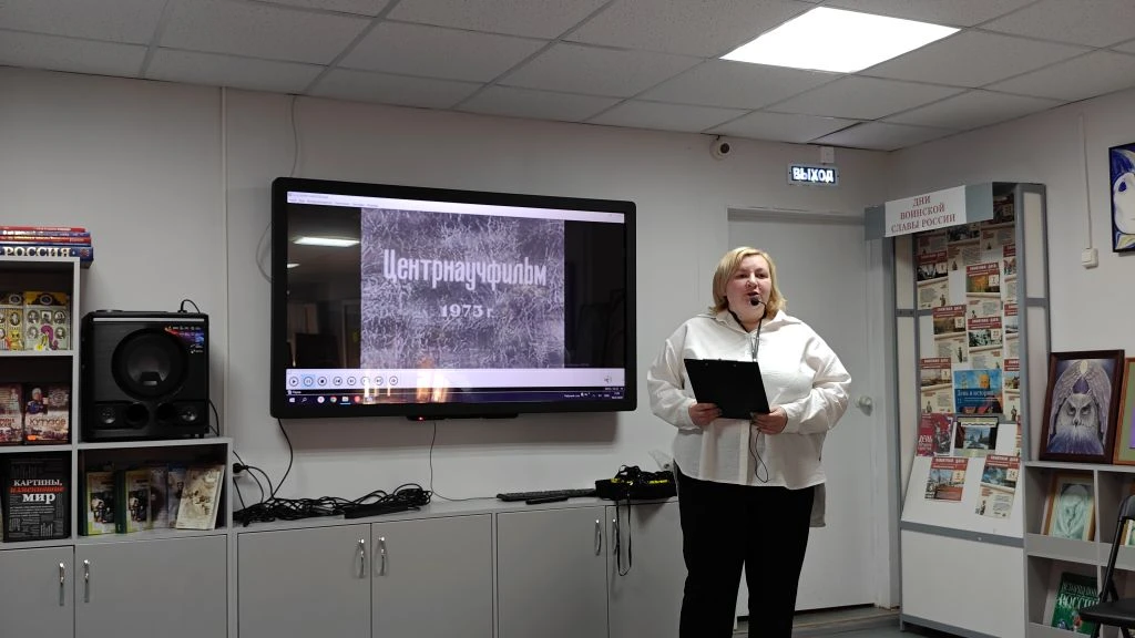 специалист библиотеки рассказывает о стаханове рядом с проектором, на котором фотографии из его жизни