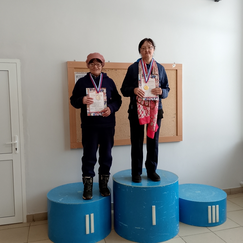 Две женщины на пьедестале: одна на 1-м месте, другая на 2-м, обе с медалями и грамотами.