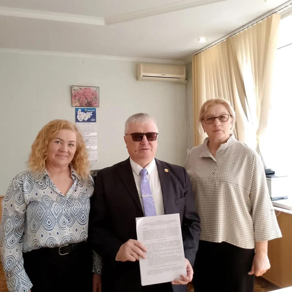 виктор кушлаков держит документ в руках, радом две женщины