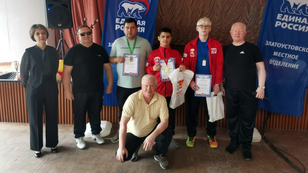 Победители мужского турнира с грамотами и медалями стоят рядом с организаторами соревнований.
