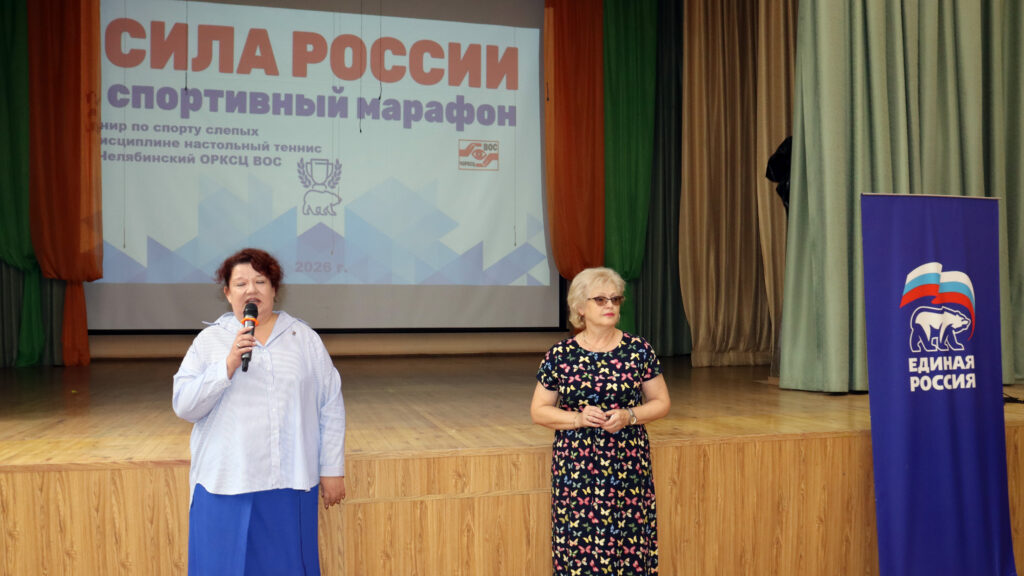 Татьяна Морозова и Надежда Топунова выступают перед участниками турнира; рядом установлен баннер партии «Единая Россия».