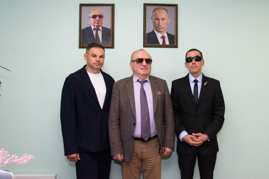 Александр Дубровский, президент ВОС Владимир Сипкин и председатель ЧООО ВОС Александр Рожков фотографируются вместе; на стене позади них — портреты руководства ВОС и Президента России.