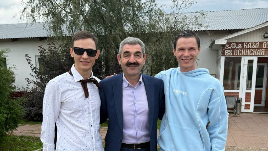 Александр Новичихин и ещё один участник форума фотографируются с подарочными пакетами на фоне оформленной фотозоны «Пермь 2026».