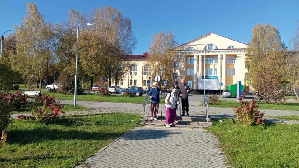 Участники Верхнеуфалейской МО ВОС со скандинавскими палками спускаются по ступеням к городскому пруду.