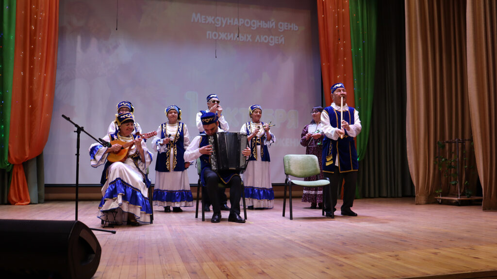 Ансамбль в национальных костюмах исполняет музыкальный номер на сцене.
