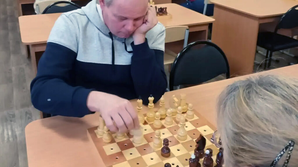 Участник чемпионата обдумывает ход за шахматной доской.