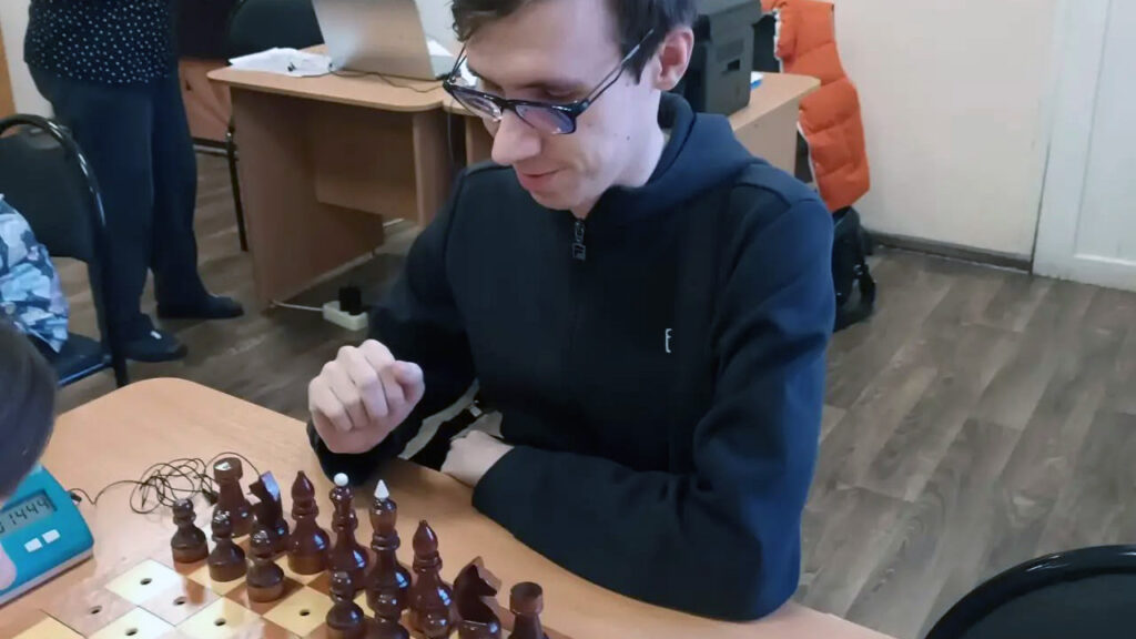 Участник чемпионата делает ход на шахматной доске.