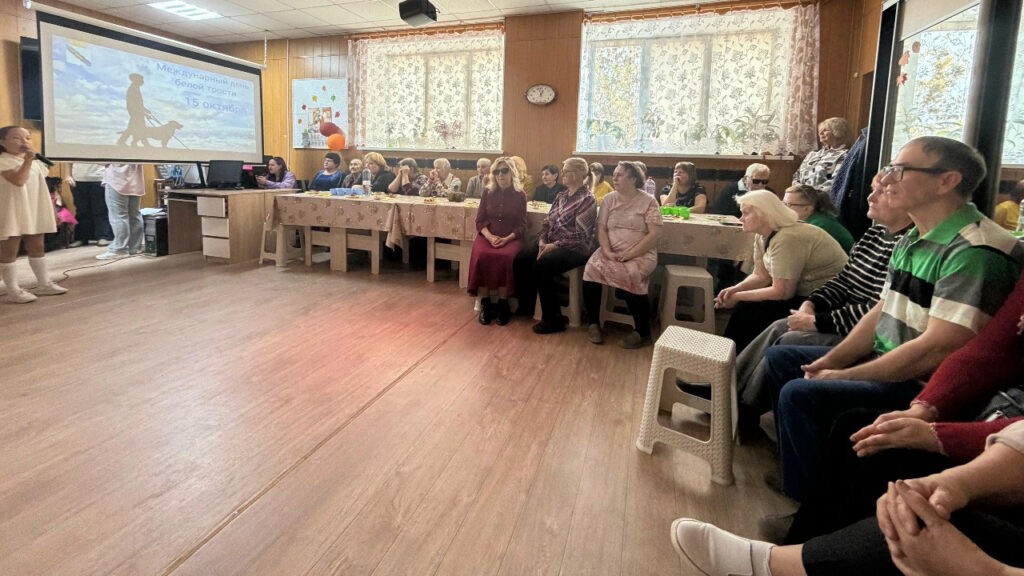 зрители мероприятия сидят возле столов 