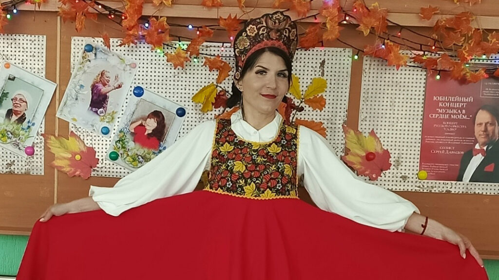 Мария Мелешкина в русском народном костюме демонстрирует красную юбку и вышитый сарафан.
